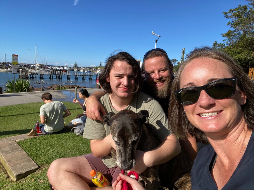 Kristie Kearney smiling with sunglasses on, son Seamus holding onto his brindle dog Ruby and husband John smiling in between Seamus and Kristie